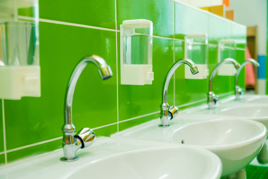 small children height sinks at a school, with a green splashback