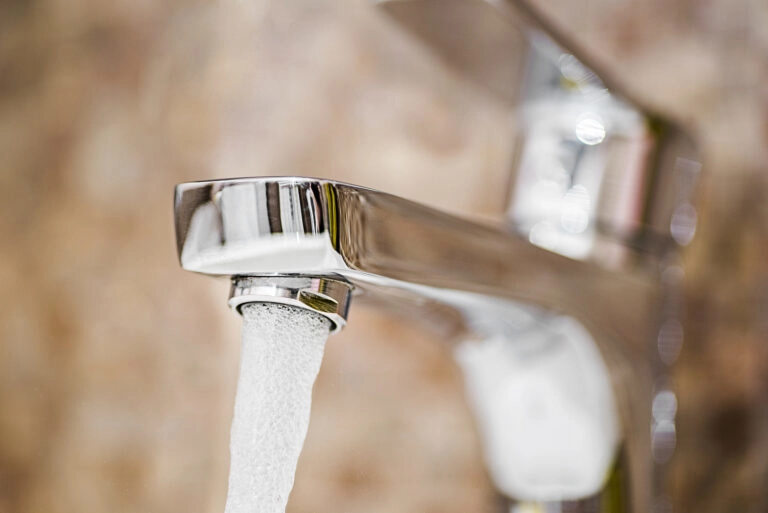A close up picture of clean water pouring out of a tap