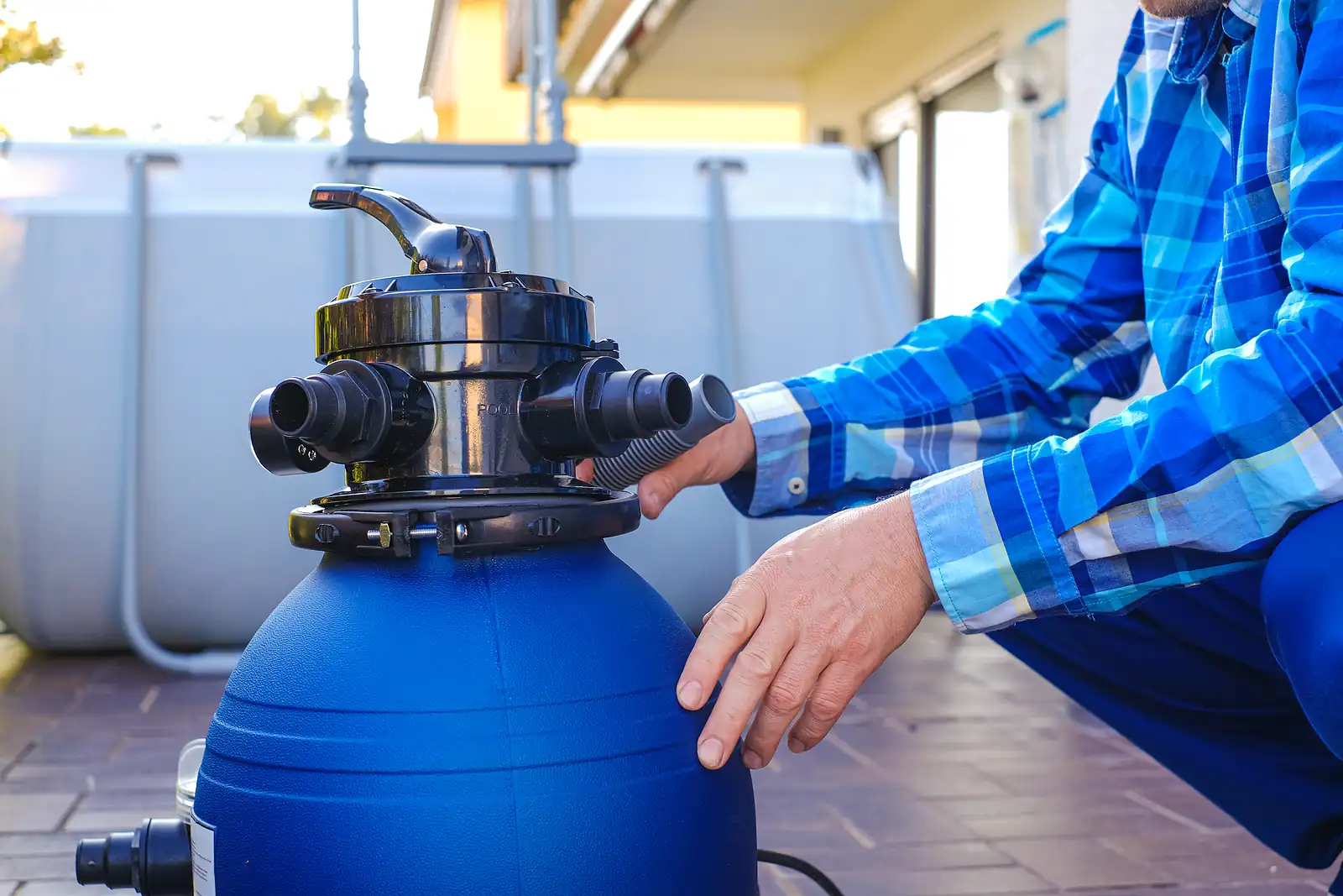 A water filter in the hands of a man on a pool background. Swimming pool cleaning equipment.